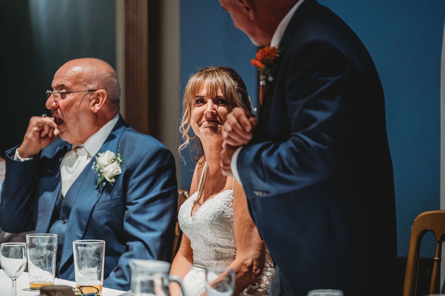 Wedding guests seated at a reception table share an emotional moment during the dinner festivities.