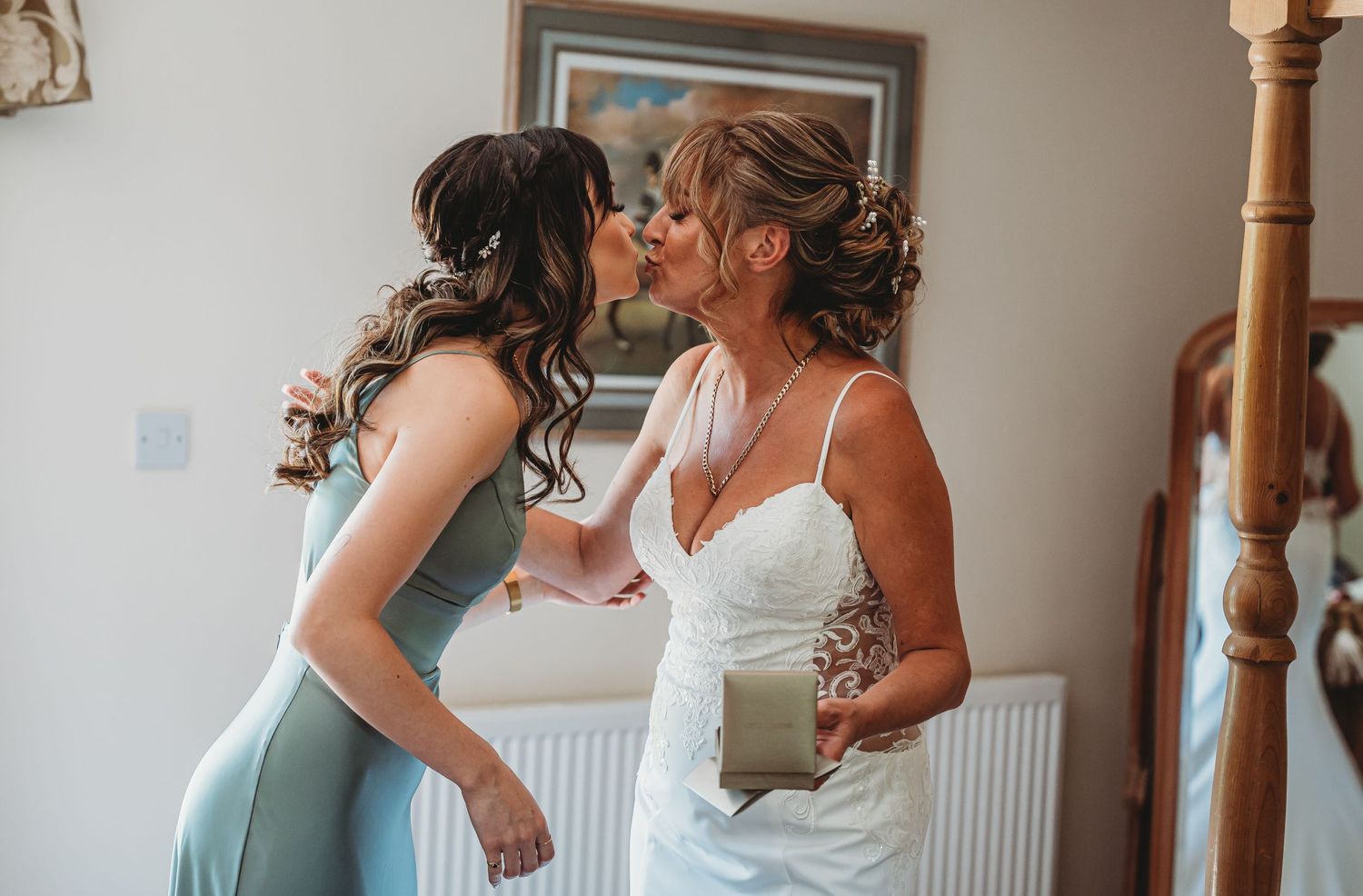 An emotional pre-wedding moment between two attendees showing joy and affection in a warmly lit room.