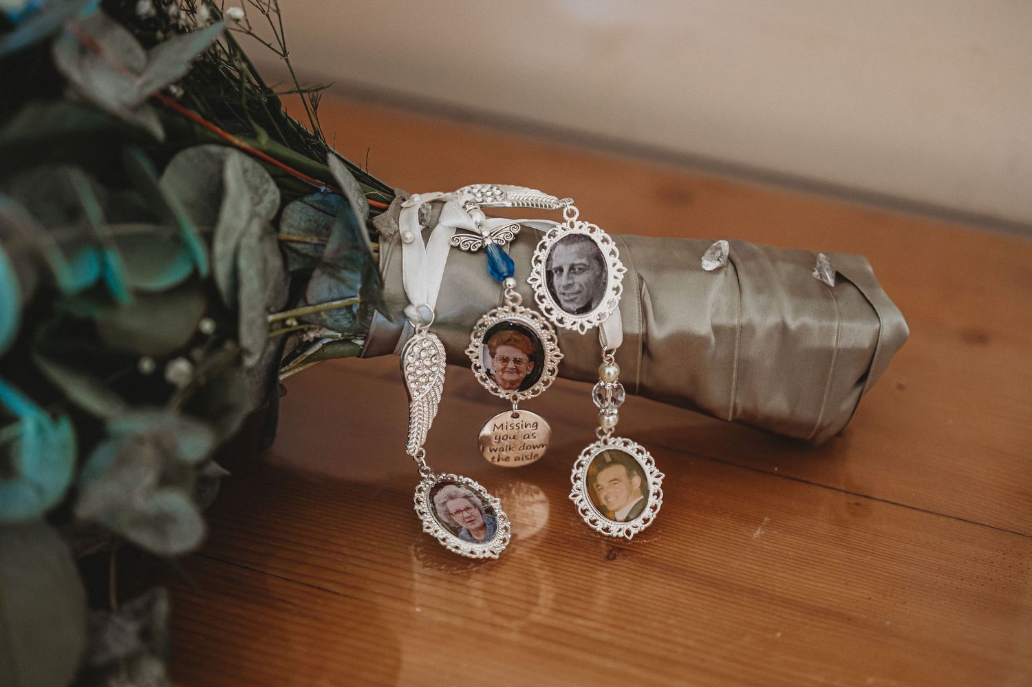 Elegant vintage-style silver and crystal bracelet displayed next to glass bottle and decorative foliage on wooden surface.