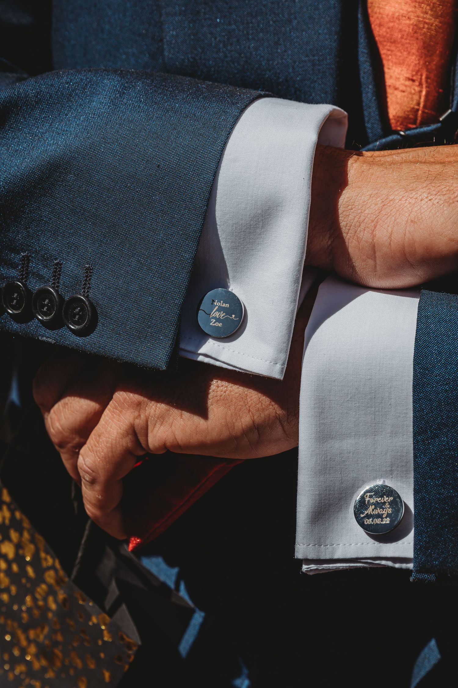 Close-up view of navy suit sleeve with white dress shirt cuffs and silver metal cufflinks.
