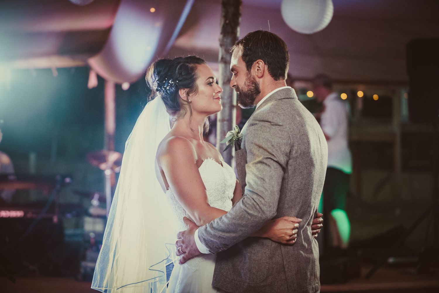 A couple shares their first dance at their wedding reception with soft lighting and bokeh effects in the background.