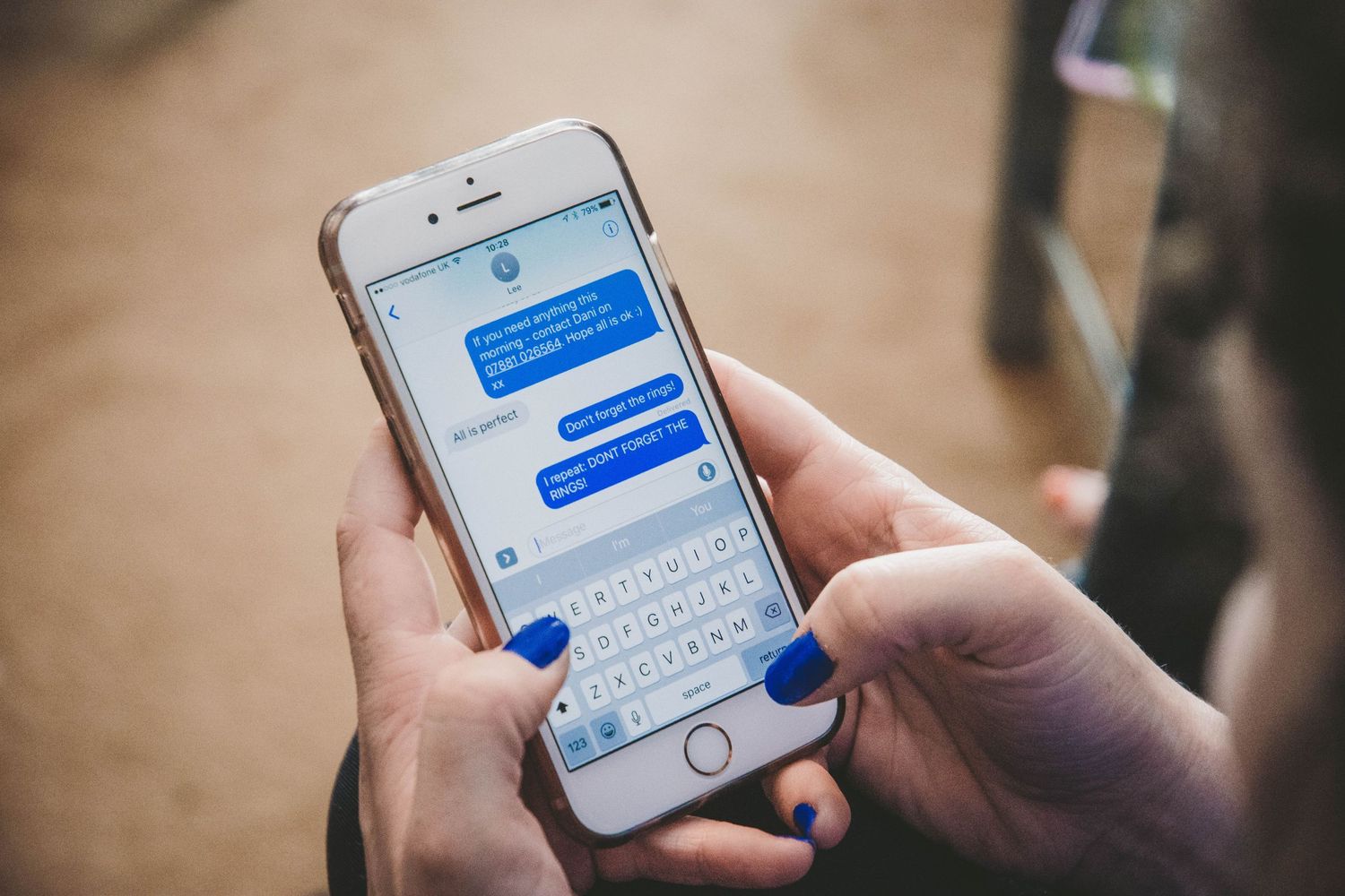 Someone's hands holding an iPhone displaying text message bubbles in blue and white in the Messages app.