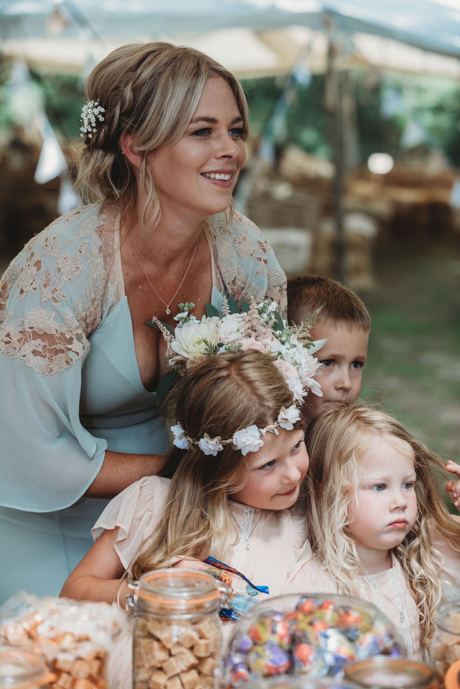 A joyful outdoor party scene with baked treats and candy jars as small children gather around a decorated table.