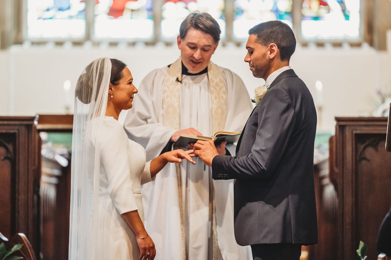 A bride and groom stand at the altar with an officiant during their traditional church wedding ceremony.
