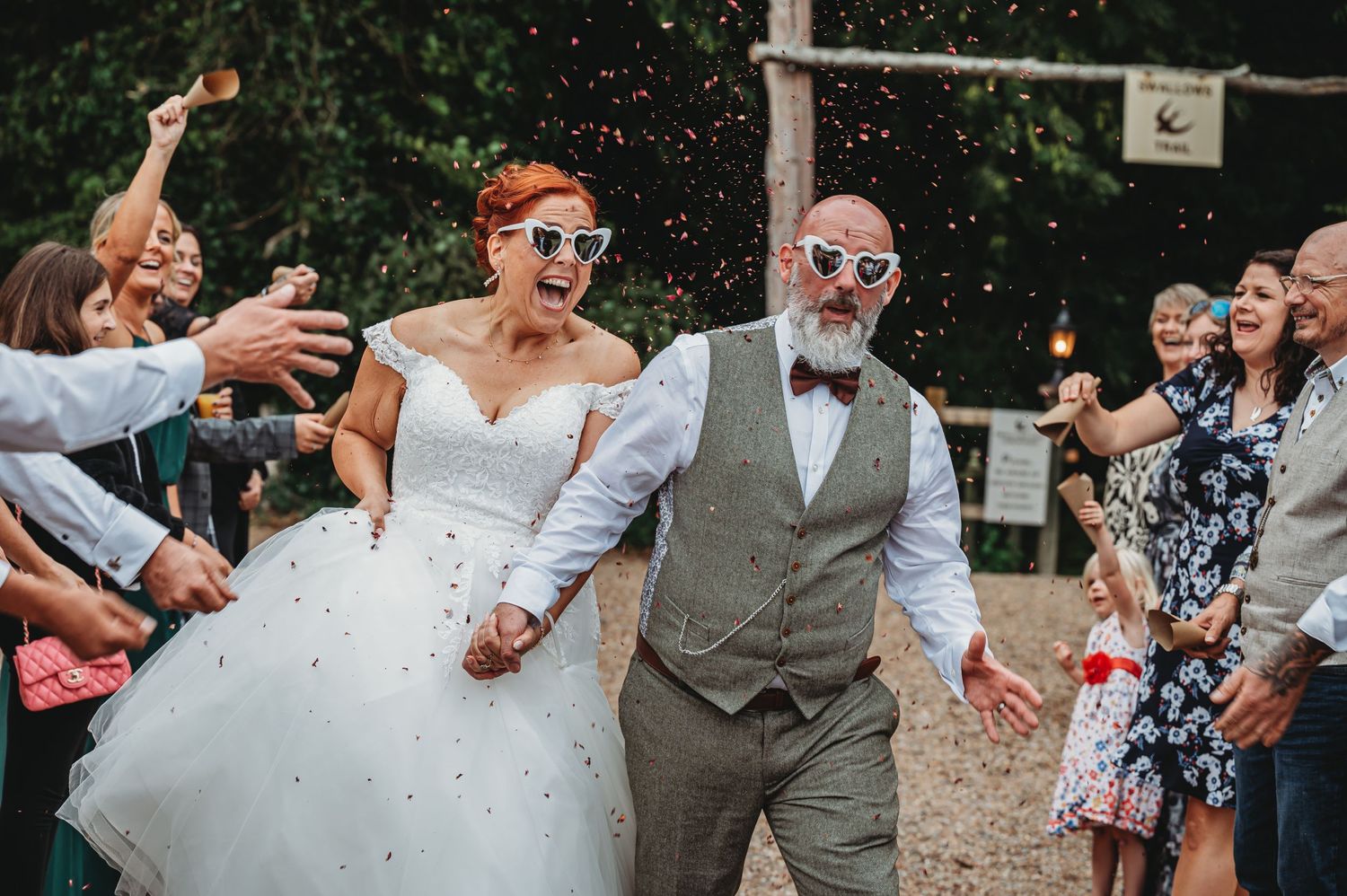 Wedding celebration with guests showering confetti on newlyweds during an outdoor reception.