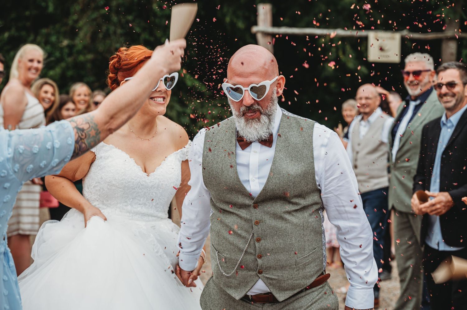 Joyful wedding celebration with the couple holding hands and guests cheering during outdoor ceremony.