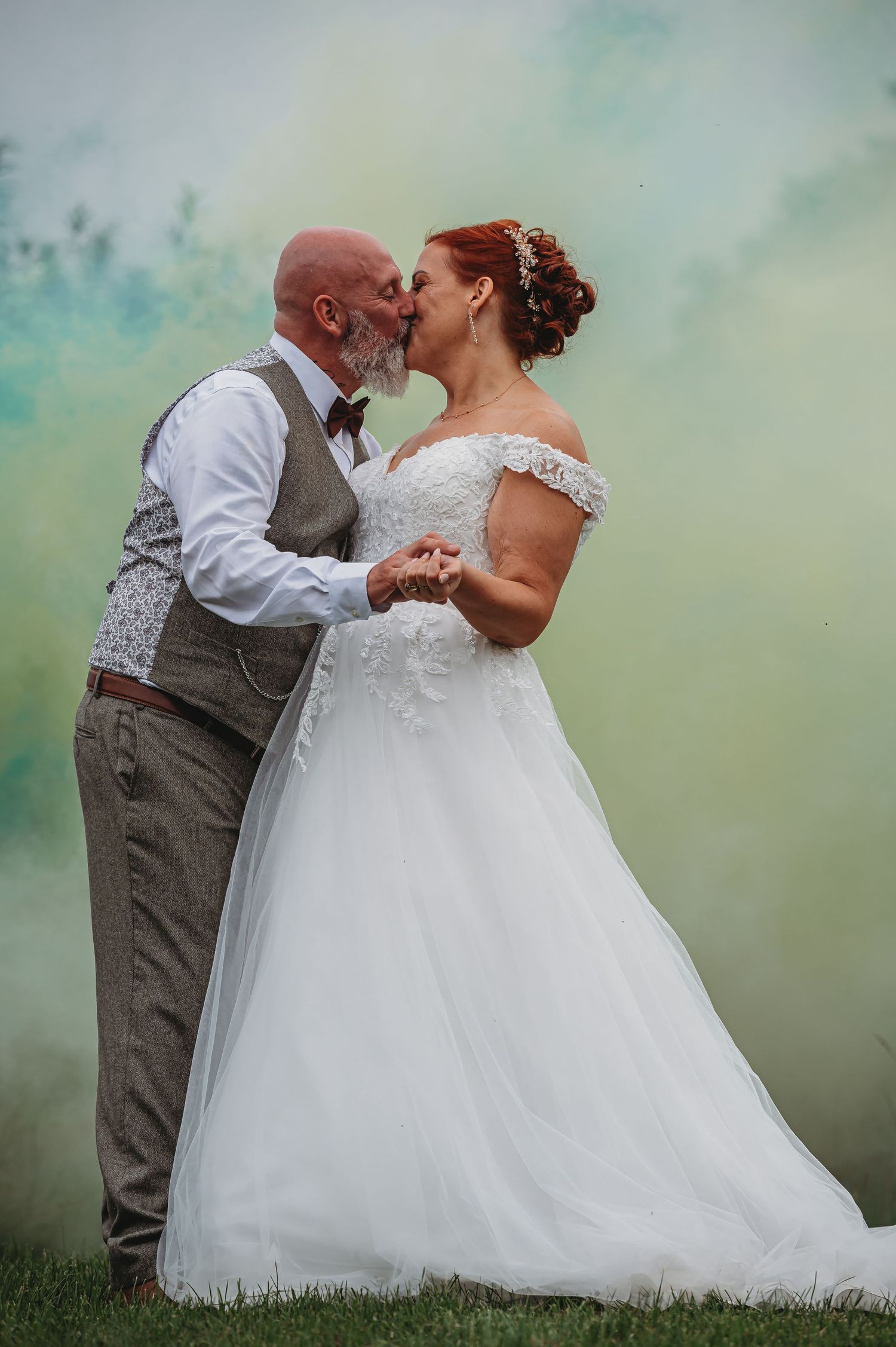 A romantic wedding moment with a couple sharing a kiss against a misty teal background.