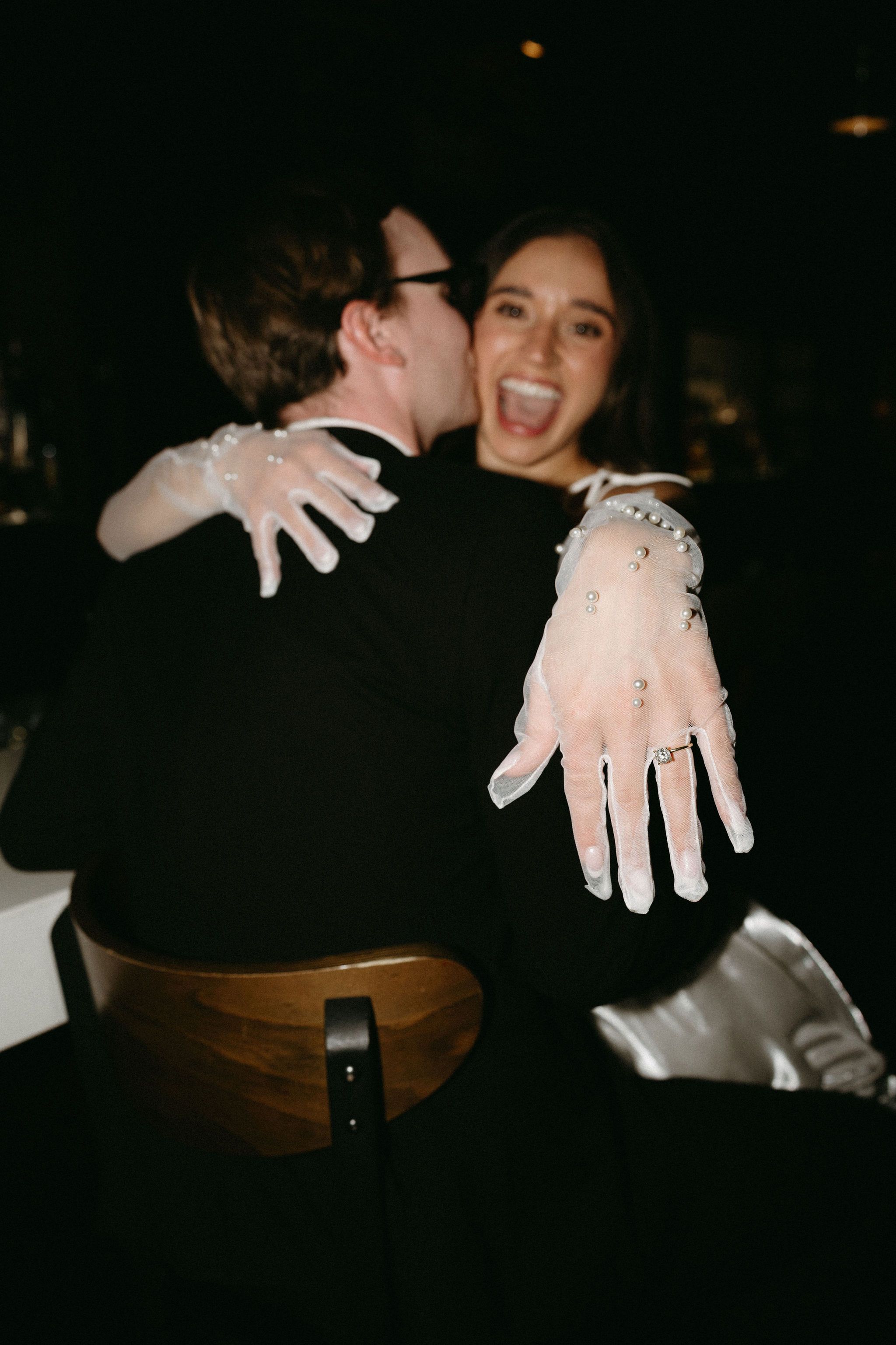 Two people embrace while showing off messy white paint-covered hands in a dark setting.