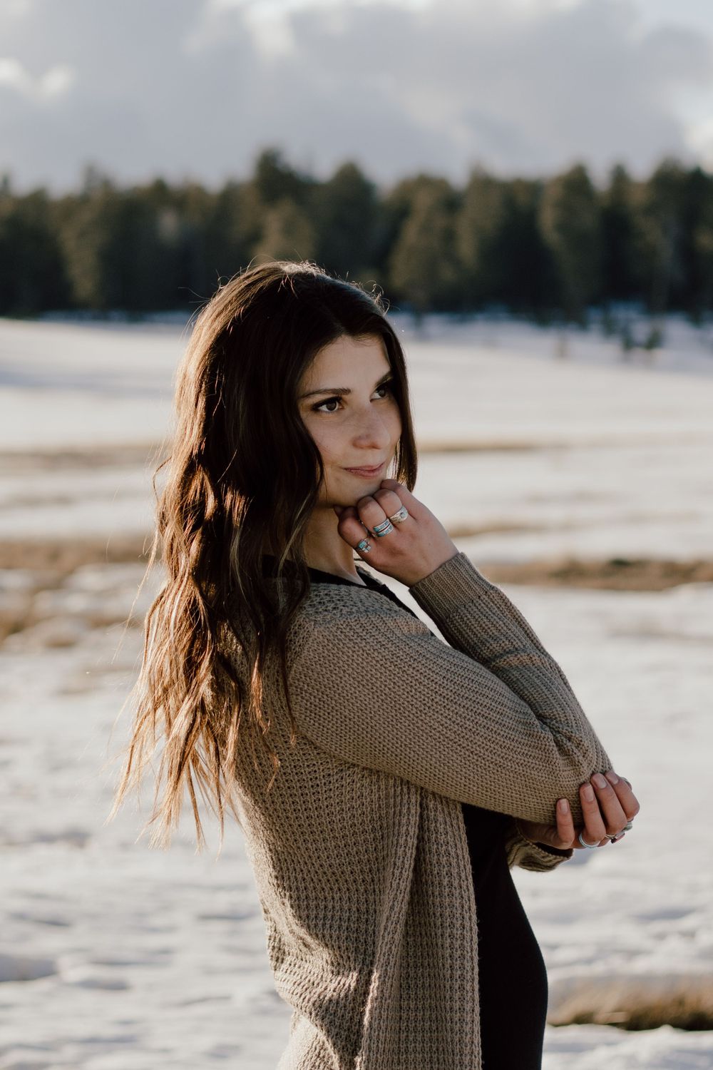 A winter portrait pose against snowy landscape wearing knit cardigan.