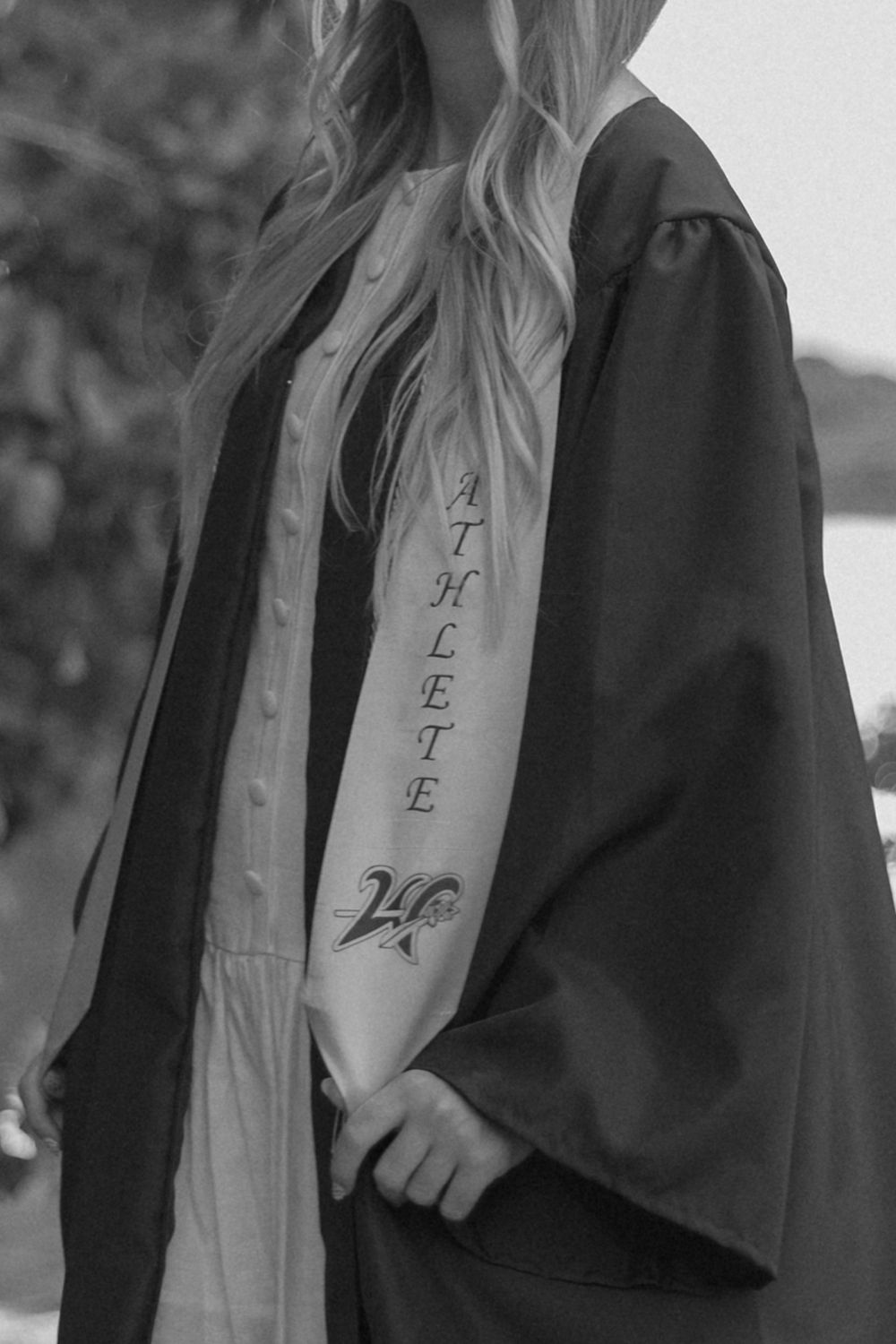 A close up of graduation stole and gown showing embroidered text details in black and white.