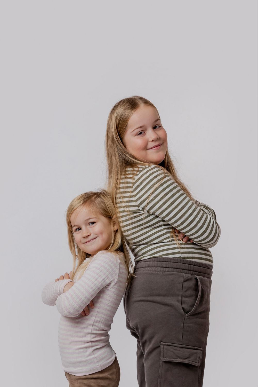 Studiefoto af to børn i stribede skjorter, der poserer ryg mod ryg. Børnefotograf Fyn