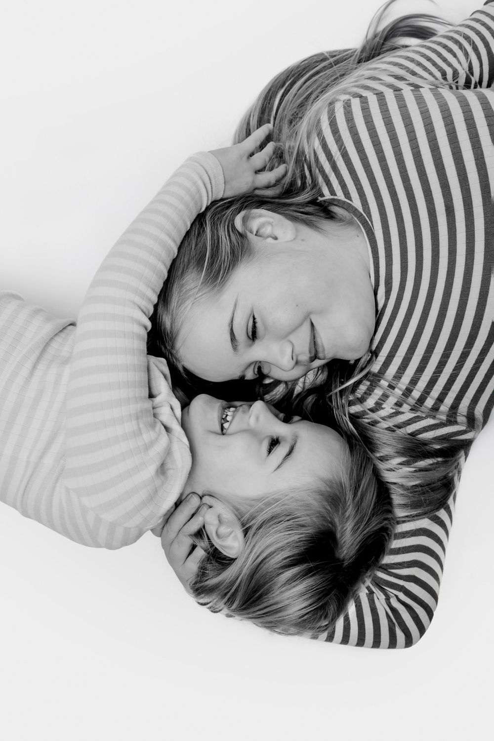 Intimt sort-hvidt luftfoto af to børn, der deler et glædesfuldt øjeblik. Børnefotograf Fyn