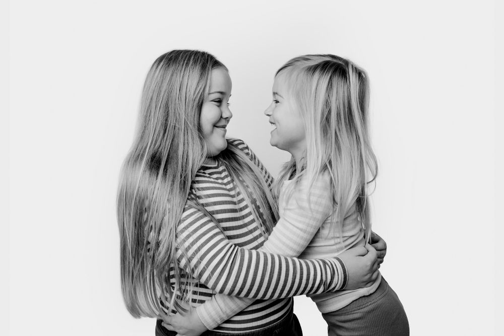 Sort-hvidt portræt af to søskende, der omfavner hinanden og viser hengivenhed. Børnefotograf Fyn