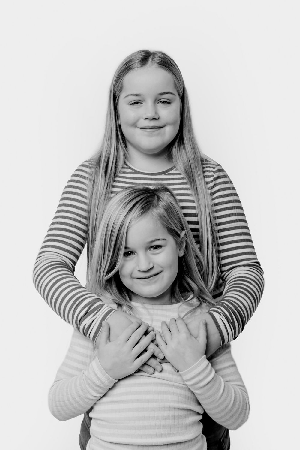 Monokromt studiefoto af to personer, der deler glædesfuld latter sammen. Børnefotograf Fyn