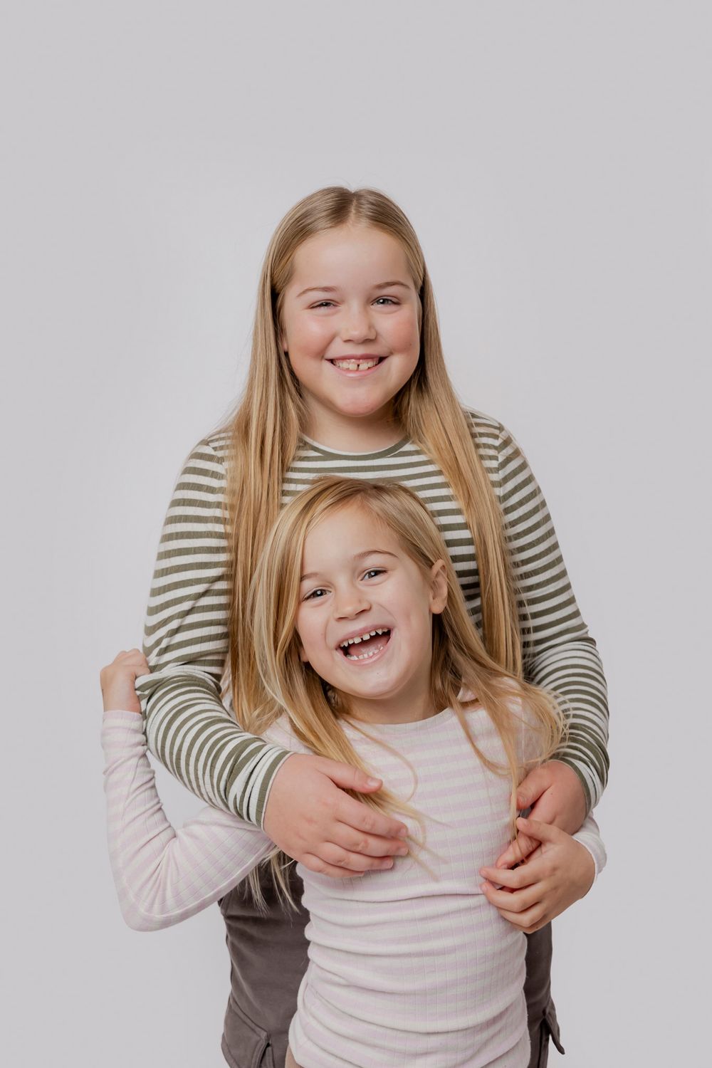Legende portræt af børn i stribede og ensfarvede skjorter foran hvid baggrund. Børnefotograf Fyn