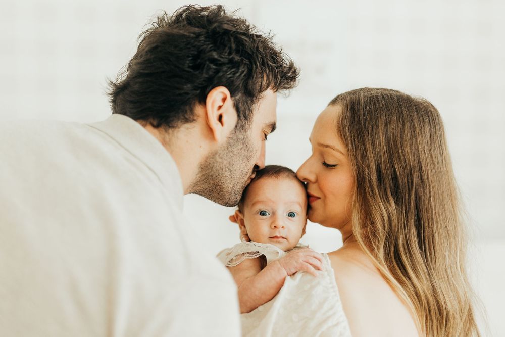 Intimate family portrait showing affectionate moments between loved ones on a light background.