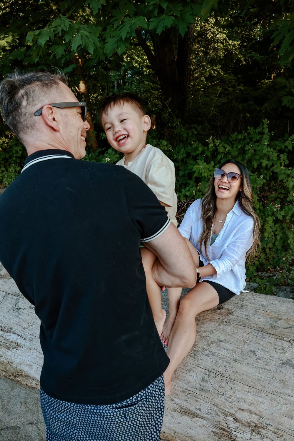 Family shares joyful laughter while spending time together outdoors on a rocky perch.