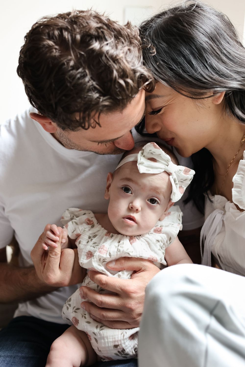 Parents showing affection while cradling their small baby in a series of intimate black and white photos.