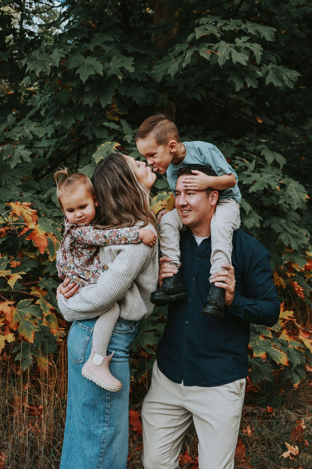 A loving family shares embraces and laughter together against a backdrop of autumn maple leaves.