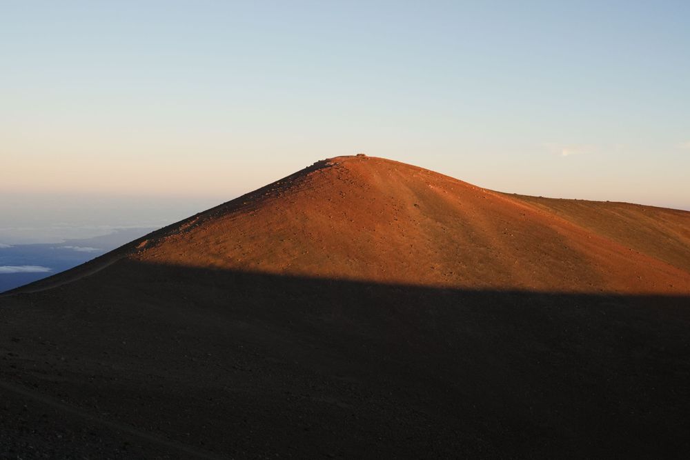 Scenic mountain landscape at sunset showing rocky terrain and peaks in warm golden light.