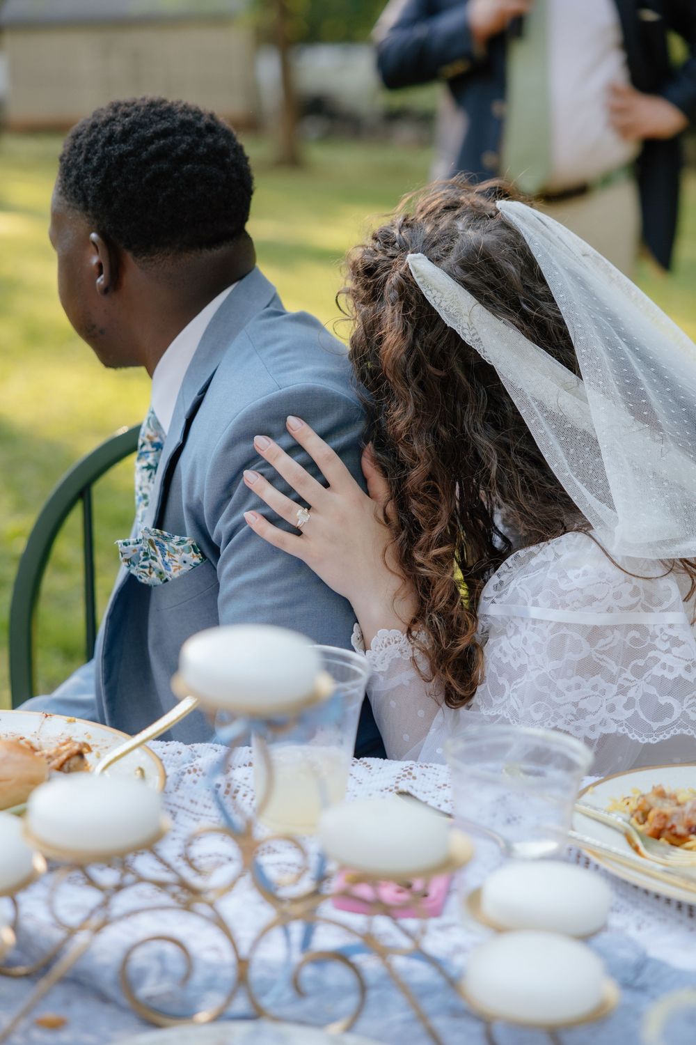 Couple sharing an intimate moment at an outdoor wedding reception with table settings visible in the foreground.