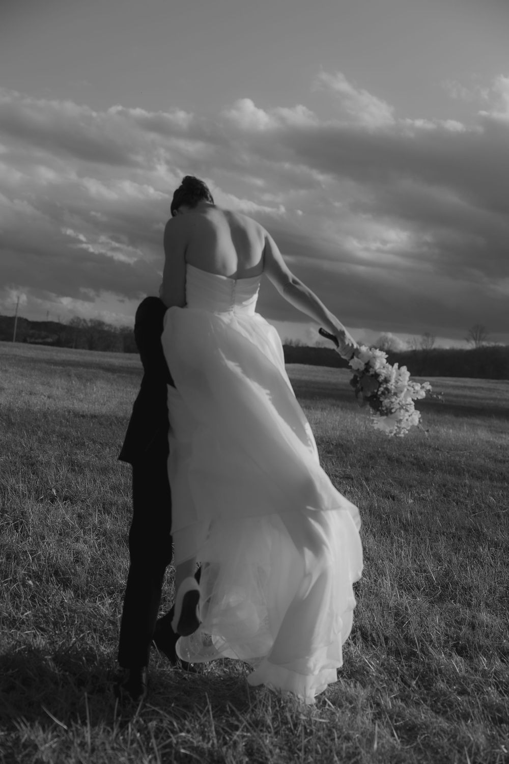 A black and white photo series shows a flowing white wedding dress billowing dramatically in the wind on a cloudy day.