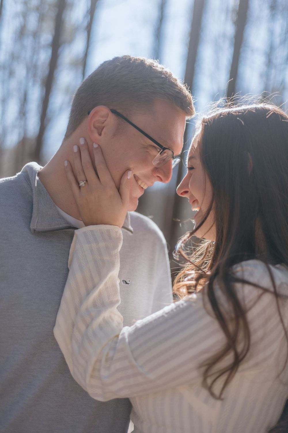 A romantic couple in white sweaters share tender moments together outdoors in a winter setting.