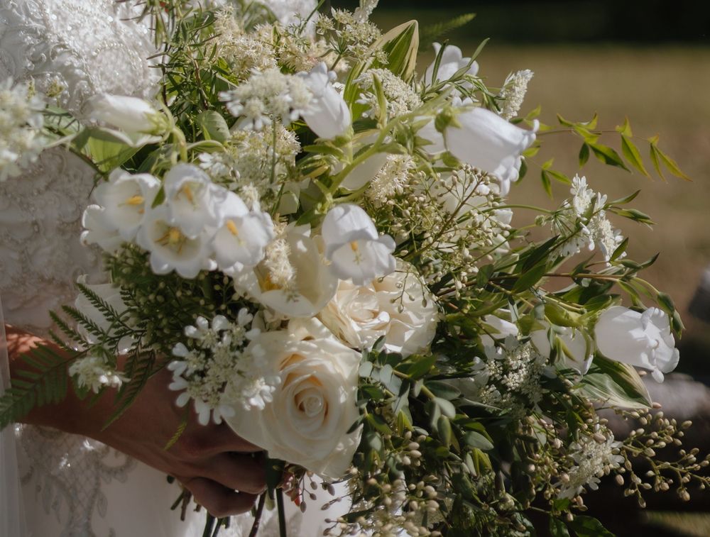 A lush white floral arrangement featuring peonies and baby's breath creates an elegant wedding centerpiece.