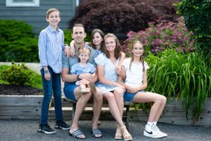 Family of six posing together on outdoor steps with garden background.