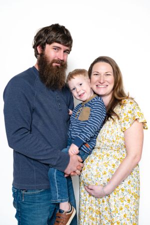 A family portrait featuring three people in casual attire against a white background.