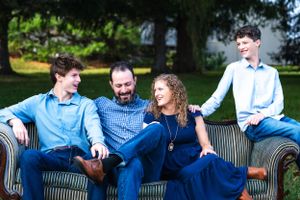 Group relaxing together on striped outdoor sofa in casual blue attire.