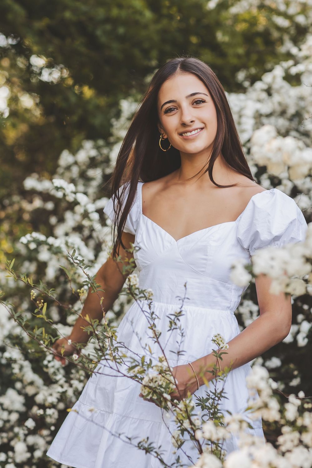 Four portrait shots showing someone in a white dress posing outdoors with flowering plants in a natural setting.