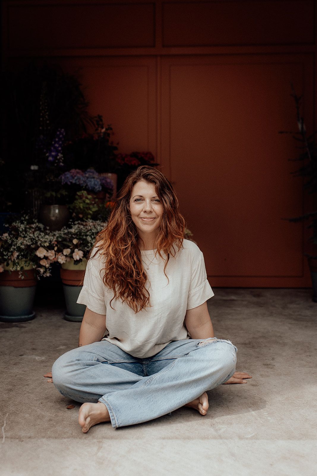 Relaxed outdoor portraits taken against a terracotta wall with potted flowers.