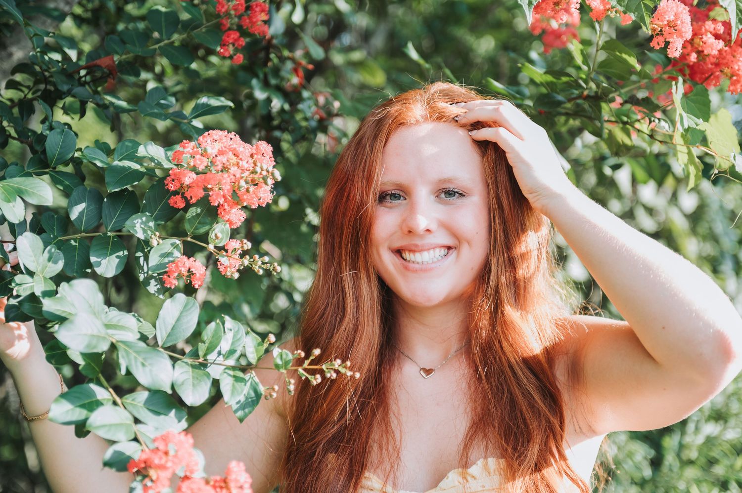 Portrait among coral roses and greenery in natural outdoor lighting.