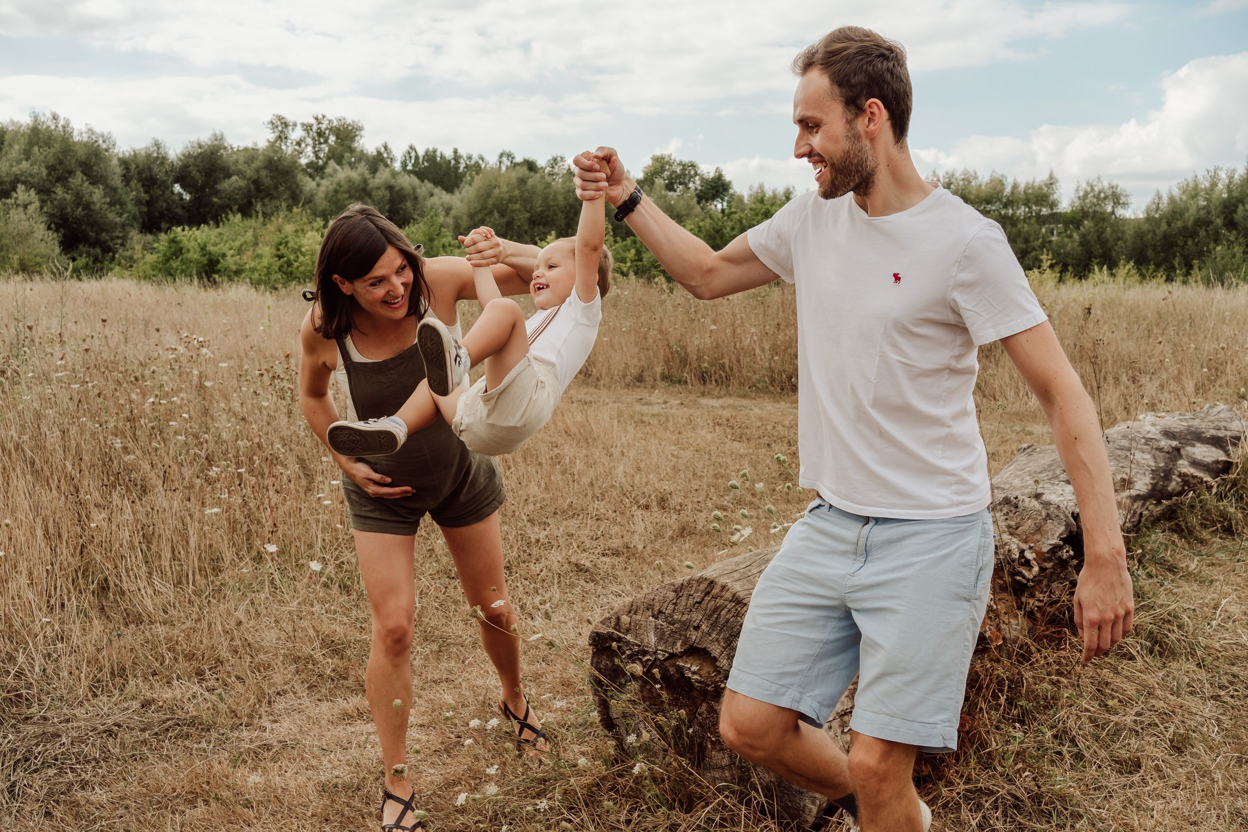 Koppel waarvan de vrouw zwanger is, samen met hun oudste zoontje, die vanop een boomstam naar voor springt