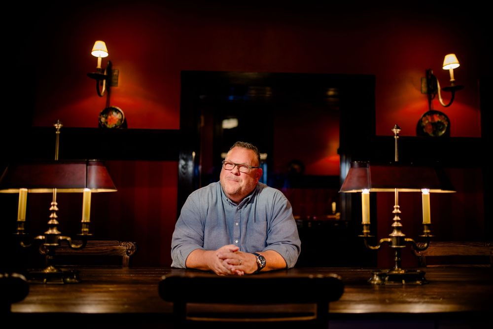 A person sits at a dimly lit bar counter with warm ambient lighting illuminating the scene.