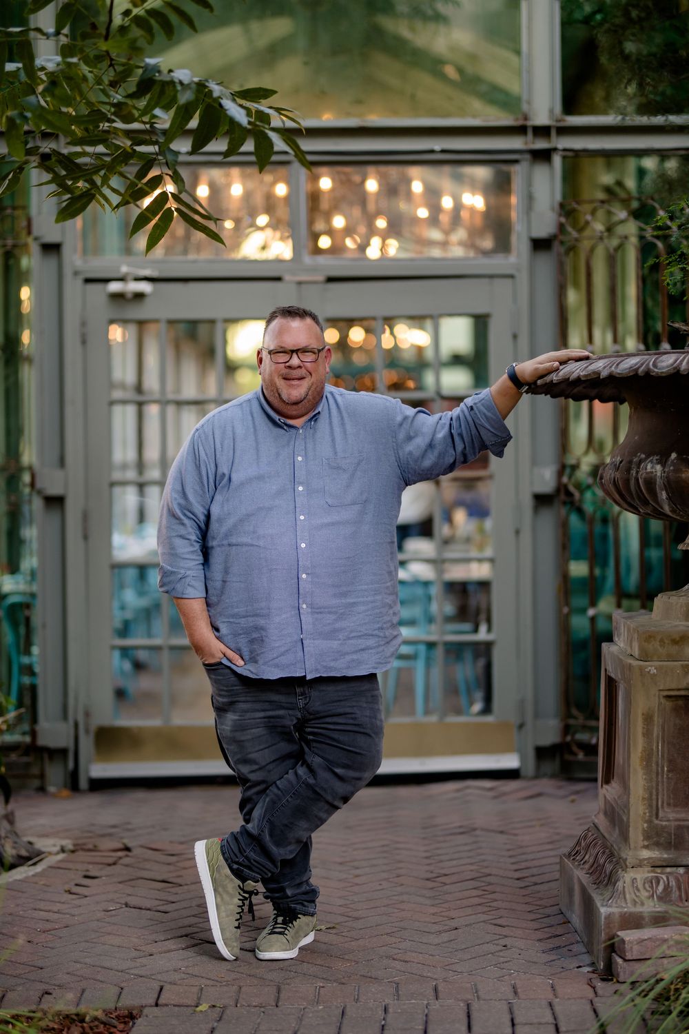 A person in a blue button-down shirt and dark pants poses playfully across a series of photos on a brick walkway.