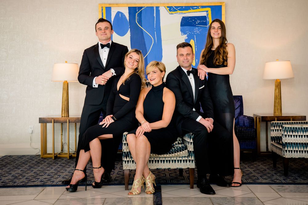 Group photo featuring people wearing formal black attire sitting and posing together in a classic portrait style.