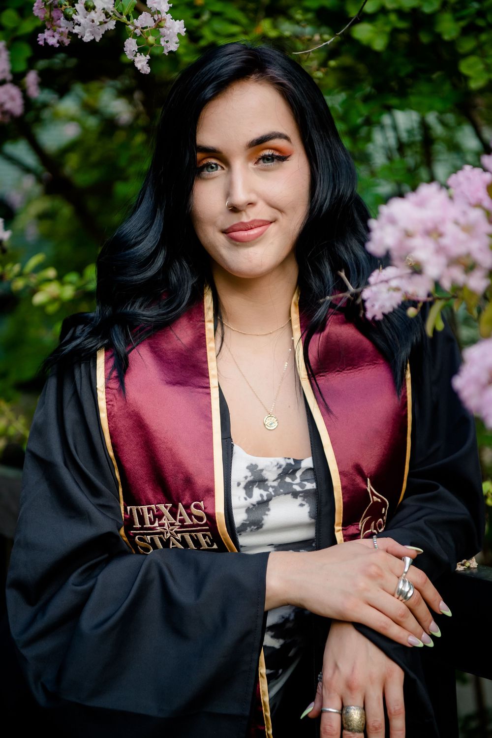 Graduation photos showing someone wearing a black cap and burgundy stole amid blooming cherry blossoms.