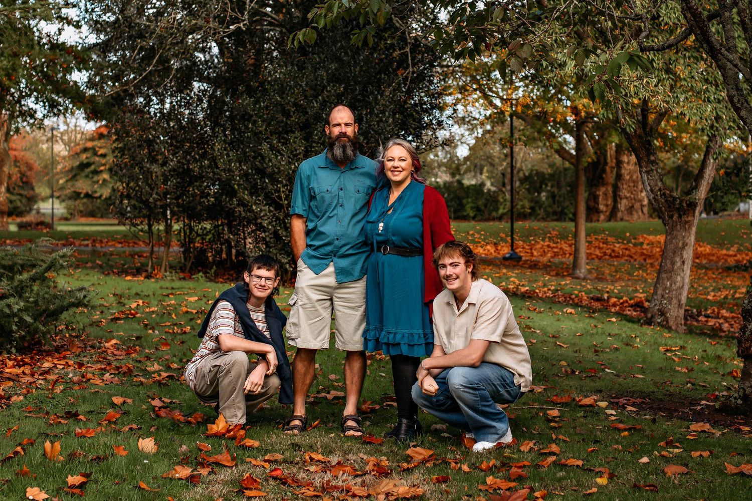 Family enjoying a warm autumn day together on fallen leaves in a Palmerston North park during golden hour.