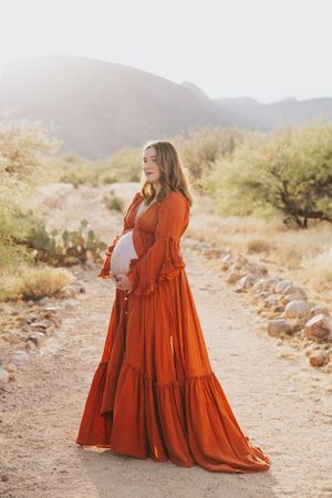 A tiered burnt orange maxi dress flows beautifully in a desert setting.