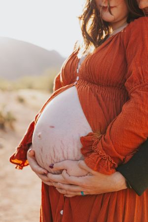 Intimate maternity photos showing baby bump details against desert scenery.