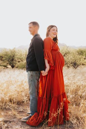 A couple shares tender moments during their maternity shoot in desert terrain.