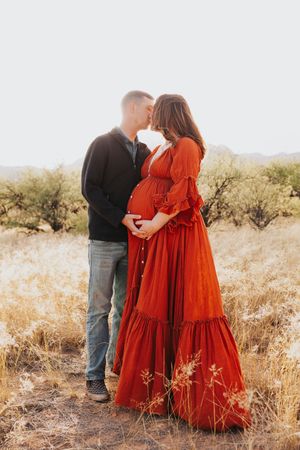 A romantic maternity photography session set against golden desert brush.