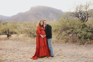 Desert maternity session featuring couple in casual attire against mountain landscape.