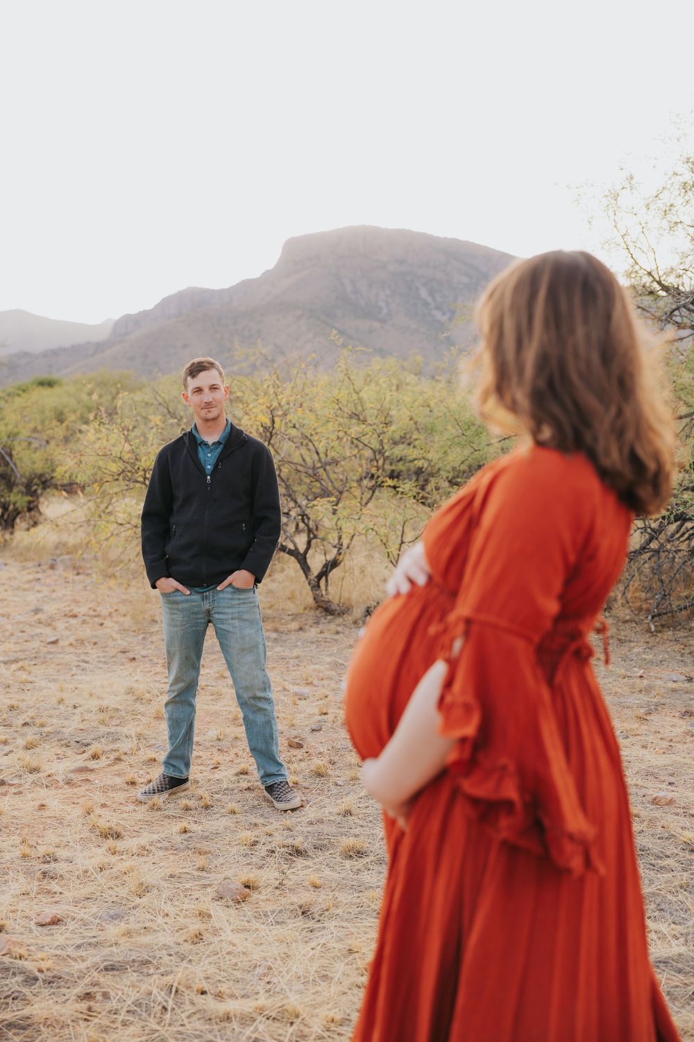 Playful desert maternity session with couple interacting at golden hour.