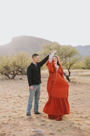 Couple sharing a dance moment in desert landscape with mountains and desert flora.