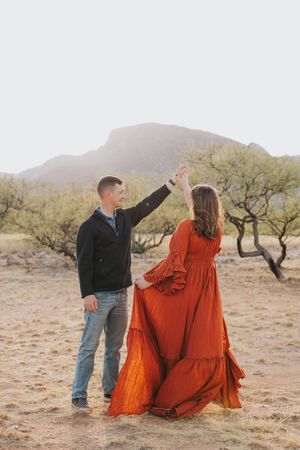 Dancing couple photographed against desert mountains and brush landscape.