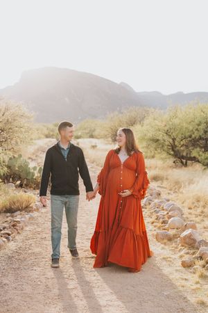 Couple walking hand in hand on desert trail wearing coordinated casual and formal attire.