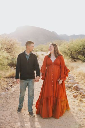 Joyful couple walking together on desert trail wearing contrasting casual and formal outfits.